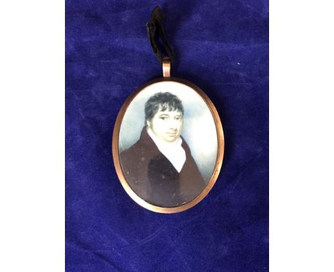 A 19th century oval portrait miniature on ivory panel of a gentleman wearing a blue overcoat and white shirt. The reverse wit