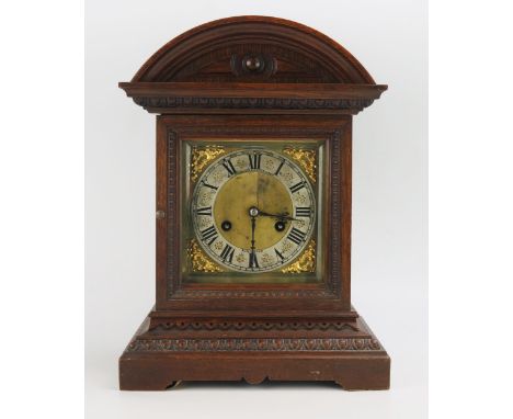 An Edwardian oak cased mantel clock, of arched outline, the 15cm brass dial with silvered chapter ring and Roman numerals, th
