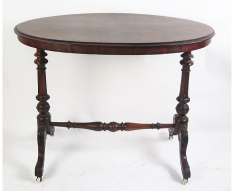 A Victorian occasional table the oval quarter veneered top raised on single column trestle end supports linked by a turned st