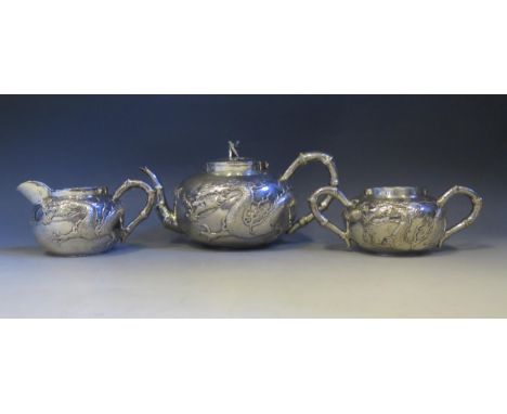 A Chinese silver three-piece tea service by Wang Hing & Co, Hong Kong, of cylindrical outline with embossed dragon decoration