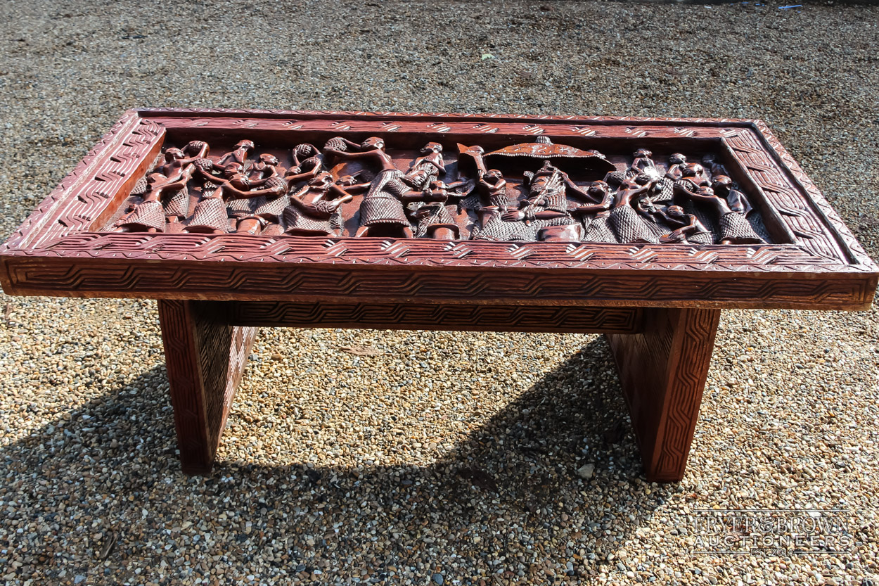 An African carved wood table, the base of two large panels carved in