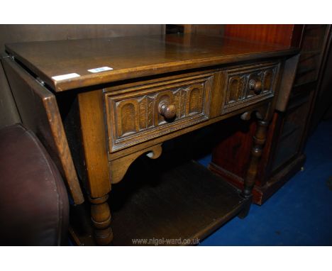 An oak side table with small folding leaves and drawer.