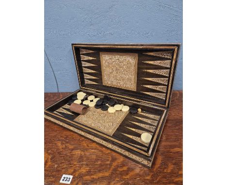 A Middle Eastern mother of pearl and micromosaic inlaid ebonised folding chess and backgammon board with dice and plastic dra