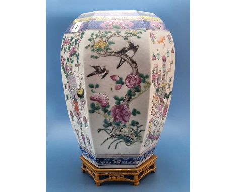 A Chinese famille rose hexagonal jar with an ochre ceramic stand, the sides of the jar painted with alternating panels of bir