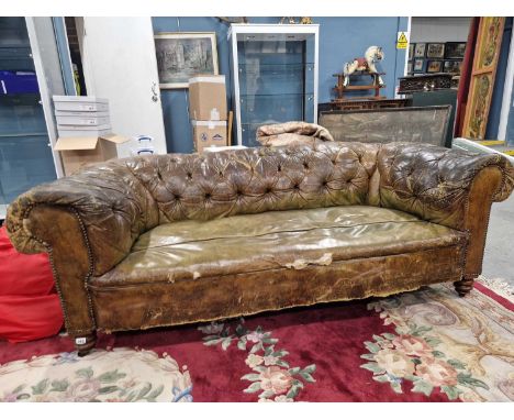 A late Victorian green leather button upholstered chesterfield, the turned front legs on black ceramic caster feet