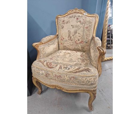 An antique French carved giltwood Louis XV style armchair covered in abusson tapestry