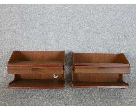 A pair of circa 1960s teak wall mounted bedside tables, the shelf over a single drawer above another shelf. H.33 W.46 D.26cm 