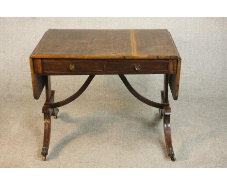 A George III mahogany and crossbanded sofa table with two drop leaves and two drawers, on end supports joined by curved brack