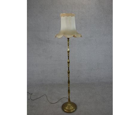 A 20th century brass standard lamp, with a multiple baluster turned stem on a circular base, with a shade. H.157cm 