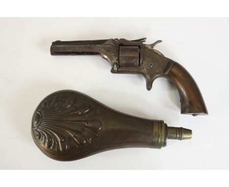 A engraved 19th century revolver along with a copper and brass 19th century repousse shell design powder flask. H.18 W.9cm. (