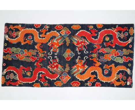  Arte Himalayana. A wooden carpet depicting four dragons chasing the flaming pearl over a blue ground  Tibet, 19th century  .