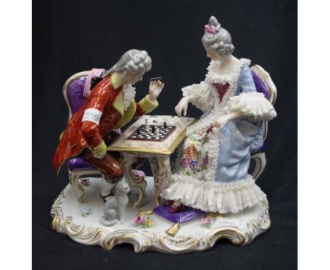German porcelain figural group depicting a lady and gentleman playing chess, with a cat seated next to them, width 20cm appro