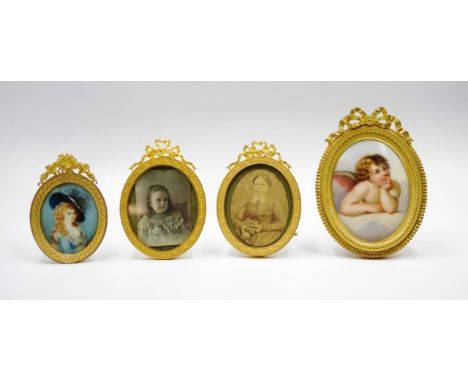 Four antique gilt brass picture frames each oval shaped brass frame with decorative pediment, each containing a portrait mini