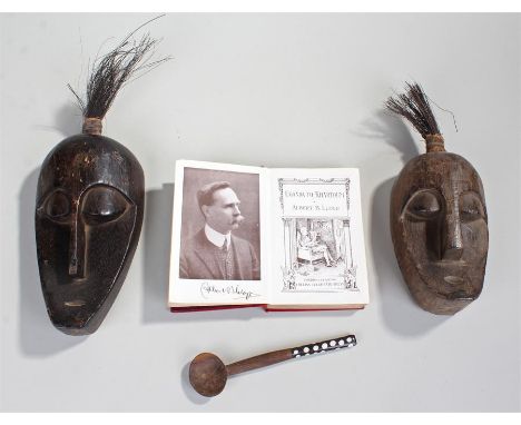 Two African masks, together with a spoon and a book by Albert Lloyd Uganda to Khartoum, (4)