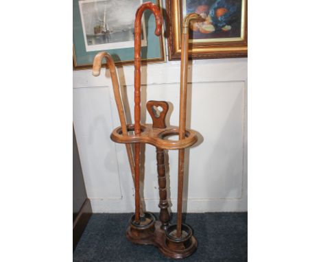 A mahogany stick stand with turned stem and metal liners, 65cm high, and three walking sticks, one with metal duck's head han