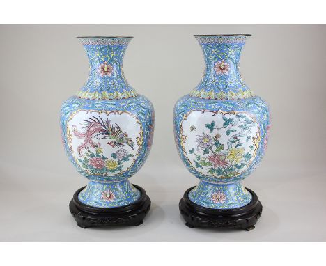 A pair of modern Chinese enamel vases decorated in blue and floral decoration, on wooden stands, 42cm high