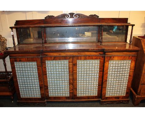 A George IV rosewood breakfront cabinet with raised mirror back and shelf, on turned supports, over four gilt metal and fabri