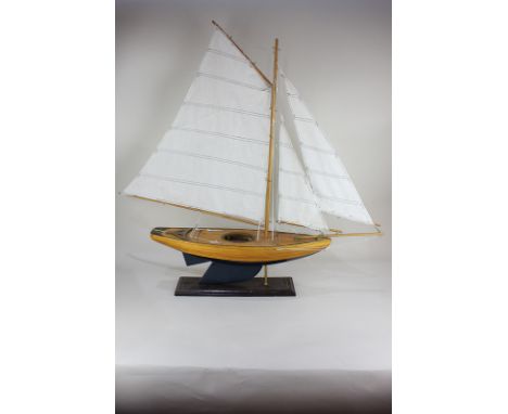 A model yacht with wooden hull and three sails, mounted on stand, yacht measures approximately 86.5cm by 97.5cm