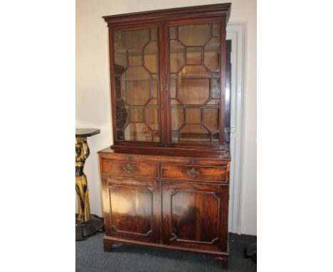 A George III mahogany bookcase with three shelves and three small drawers enclosed by twin astragal panel glazed doors, on ba