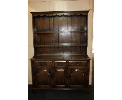A reproduction oak dresser, panel back with two shelves, on base with three drawers and cupboards, on bracket feet, 137cm