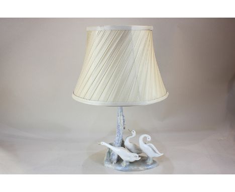 A Lladro style porcelain table lamp modelled with three geese by a tree trunk, 26cm high