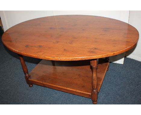 A yew oval coffee table with rectangular under shelf, on baluster supports, 119cm