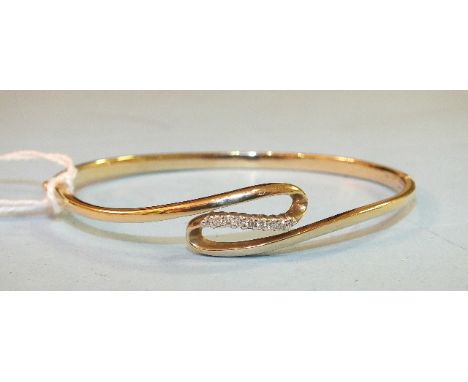 A 9ct yellow gold hinged bangle of twist design, claw set nine brilliant cut diamonds, diamond weight 0.1ct, internal dimensi