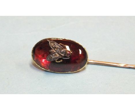 A Victorian stick pin collet-set an oval garnet cabochon, surmounted with a diamond-set fly motif, garnet 20 x 11mm, total le