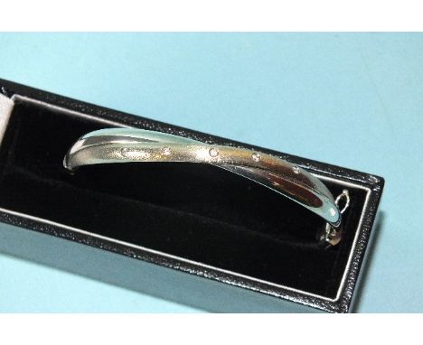 A 9ct white gold hinged bangle set five white stones, 56 x 50mm inside measurement, 6.4g, boxed.