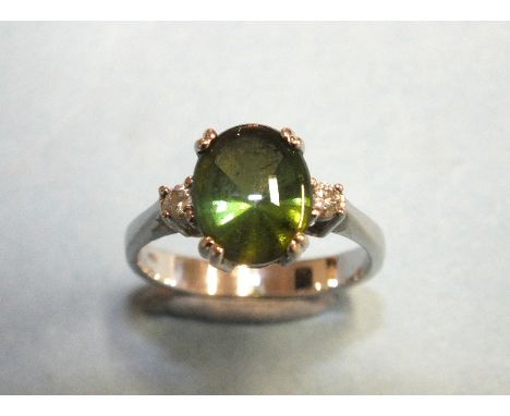 A green tourmaline and diamond ring, the dome-top tourmaline of approximately 2.52cts, claw-set between two brilliant-cut dia