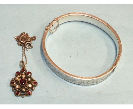 An Austrian silver-gilt garnet and pearl cluster pendant with filigree mount, (drop lacking) and a silver hinged bangle, (2).
