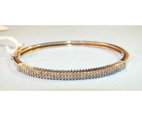 A 9ct yellow gold hinged bangle, one half claw set a total of eighty-four brilliant cut diamonds in two rows, internal dimens