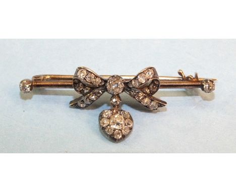 A Victorian bar brooch with central diamond-set bow, with diamond-set heart pendant below, between diamond-set terminals, the