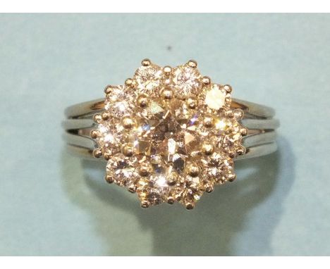 A diamond cluster ring claw-set a brilliant-cut diamond of approximately 0.94cts, within a surround of ten brilliant-cut diam