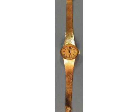 Longines, a lady's 18ct gold oval manual wrist watch, the gold face with baton numerals, on tapered flexible bracelet, 22 x 1