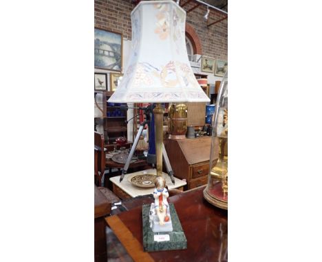 A 1930S TABLE LAMP, decorated with a ceramic study of a child knitting (head repaired) on a marble base