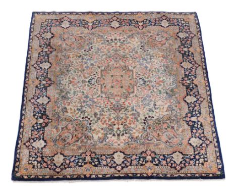  A Kirman carpet,   the cream field decorated profusely with polychrome floral branches, within a navy border, approximately 