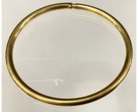 A yellow metal hollow tubular compression bangle, stamped 585, 10g 