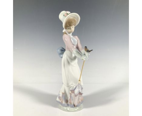 Glossy figure of a woman in a bonnet and gloves gazing upon a bird that has landed on her hand. Lladro backstamp. This item h