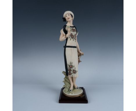 Handcrafted figurine depicting a young woman in a flowing gown gracefully holding a small bouquet of flowers while resting on