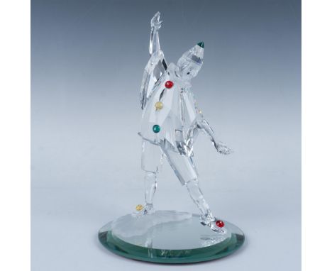 A whimsical jester, adorned with vibrant green, yellow, and red crystal accessories, strikes a playful pose his arms opened w