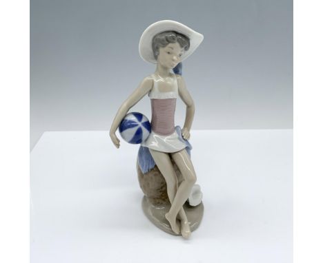 Glossy figure depicting a young girl in beach attire as she hangs out by a rock with a beach ball by her side. Lladro backsta