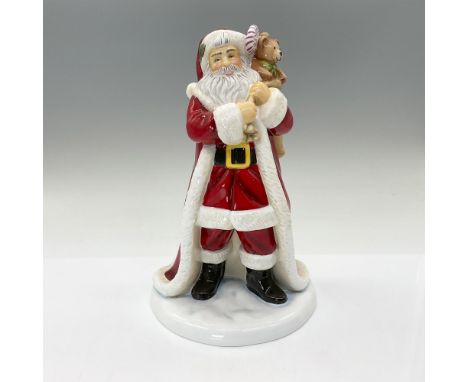 This exquisite handmade and hand-decorated bone china figurine showcases Santa Claus standing proudly with a bag of toys drap