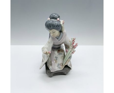 Elegant figure of a woman modeling a floral decorated kimono as she kneels holding long stemmed flowers. Lladro backstamp. Th