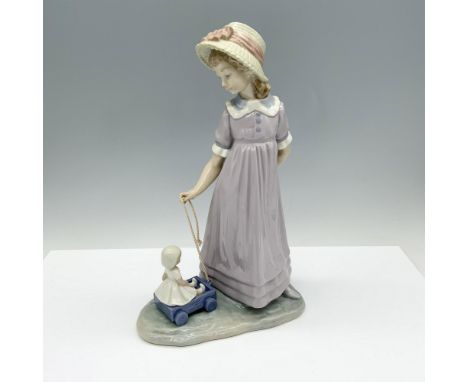 Glossy figure depicting a young girl in a lavender dress playing with her wagon by pulling it with a cord. Lladro backstamp. 