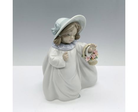 Glossy figure of a young girl in a white flowy dress and bonnet as she holds a basket of flowers. Lladro backstamp. This item