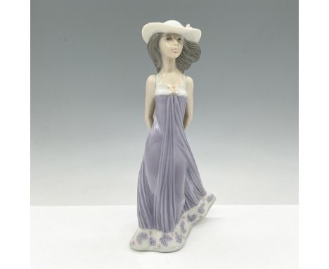 Young figure dressed in lavender dress with matching hat adorned with flowers. Lladro backstamp. This item has its original b
