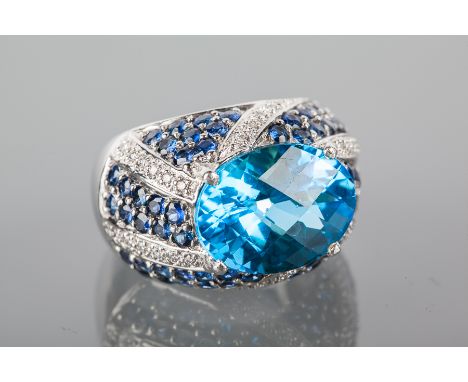 EIGHTEEN CARAT WHITE GOLD TOPAZ, SAPPHIRE AND DIAMOND BOMBE DRESS RING
set with an oval mixed cut topaz 15x11.5mm, with pave 