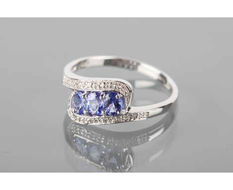 TANZANITE AND DIAMOND DRESS RING
set with three oval tanzanite flanked by two rows of diamonds, in a twist setting, in nine c