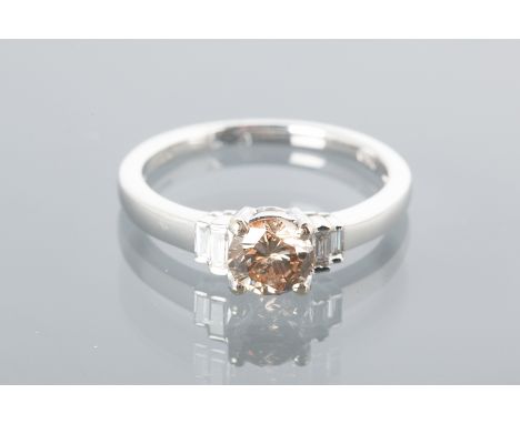 COLOURED DIAMOND RING
set with a central round diamond with brown tones flanked by two baguette cut diamonds, in eighteen car